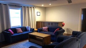 A living room with two dark blue sofas, a wooden coffee table, and a patterned rug. - Huge House Fantastic for Families and friends (Anglers Reach)
