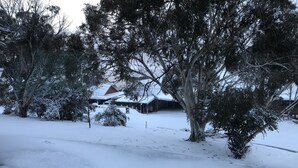 A snow-covered landscape with trees and a building with a sloped roof. - Huge House Fantastic for Families and friends (Anglers Reach)