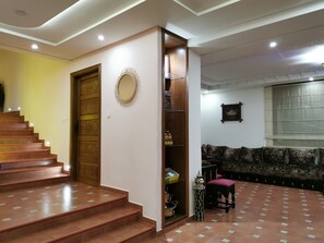 Eine Treppe führt zu einer Tür, ein dekorativer Spiegel, ein Sofa und ein gemustertes Teppich.
