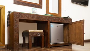 A compact room with a wooden desk, a small stool, and a built-in mini-fridge. - Dar Zayane (Mouha ou Hammou Zayani)