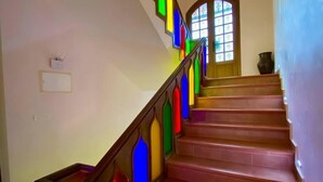 A staircase with colorful stained glass panels on the railings and a wooden handrail. - Dar Zayane (Mouha ou Hammou Zayani)