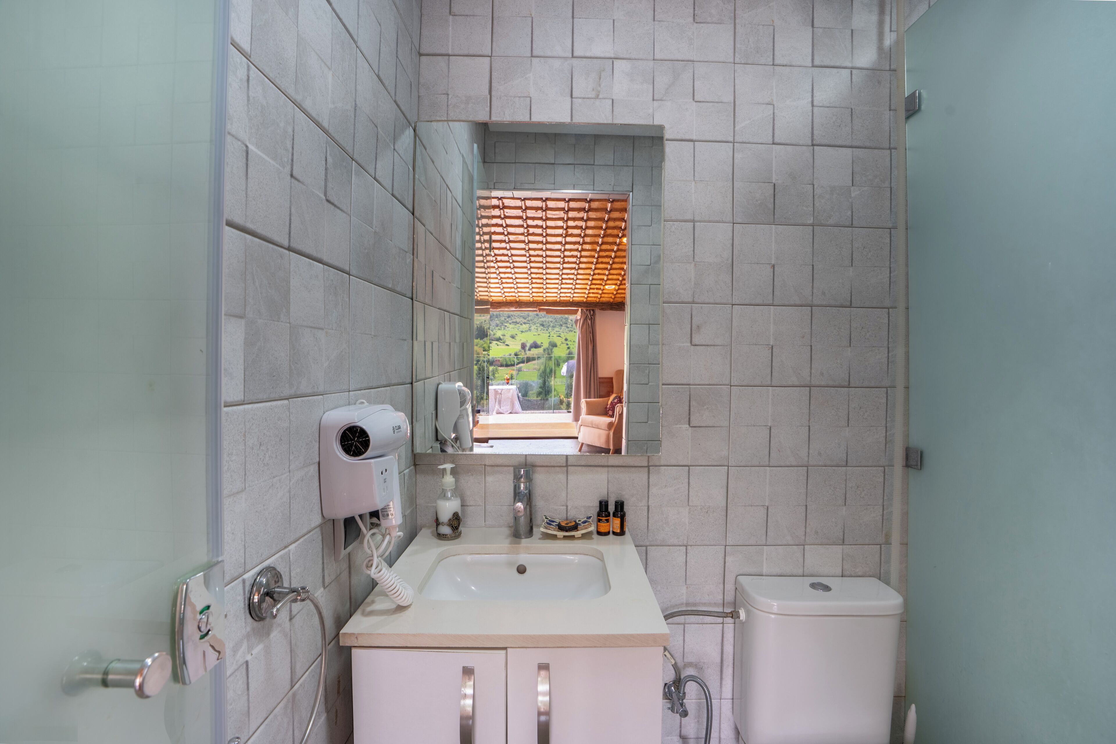 A bathroom with a large mirror, a sink, a toilet, and a shower.