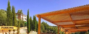 Eine hölzerne Pergola, ein Parkplatzschild und ein Gebäude mit Steinverkleidung.