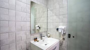 A bathroom with a white sink, a mirror, and a hairdryer mounted on the wall.