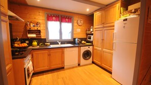 Una cocina compacta con muebles de madera, lavadora, microondas y refrigerador.
