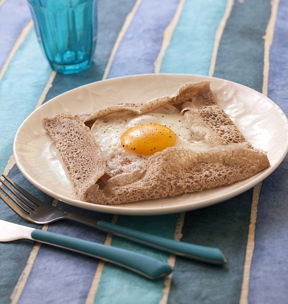 A plate with a folded piece of bread and a fried egg on a striped tablecloth.