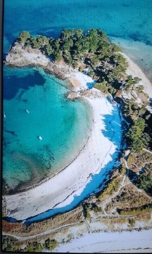 An aerial view of a coastal area with clear blue waters, sandy beaches, and dense greenery.