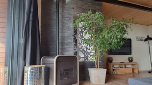 A modern living room with a fireplace, a potted plant, a television, and a wooden floor. - VILLA 260€ 12 People Ideal for large groups (hikers, families, etc.) (Plouenan ( kerlaudy))