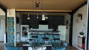 A modern kitchen with a central island, bar stools, and pendant lighting. - VILLA 260€ 12 People Ideal for large groups (hikers, families, etc.) (Plouenan ( kerlaudy))