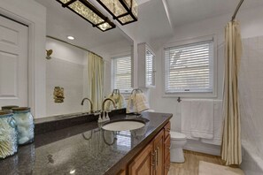 Une salle de bain avec un grand miroir, deux lavabos, des toilettes et une douche.