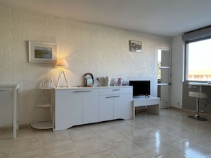 A modern living room with a white cabinet, a TV, a lamp, and a small table. - Spacious 2-Bedroom Apartment near Banyuls-sur-Mer Port (Banyuls-sur-Mer)