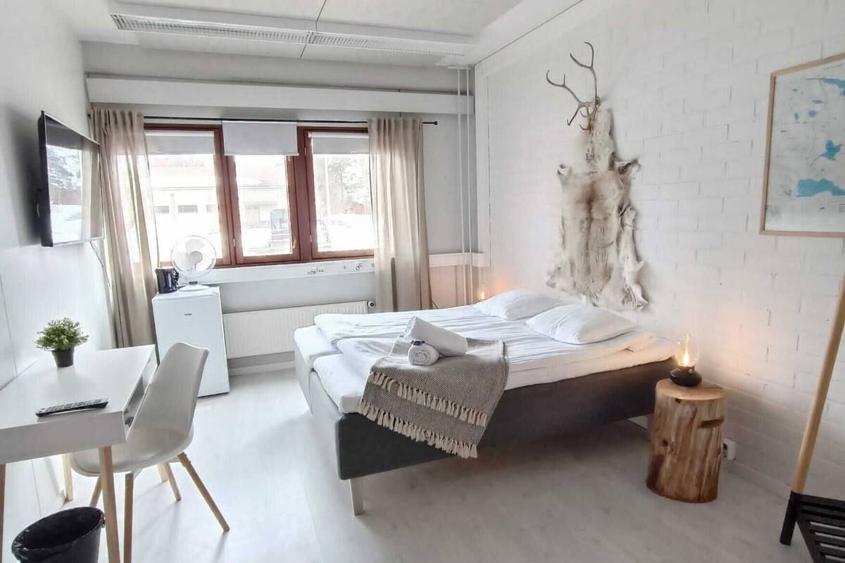 A modern bedroom with a bed, bedside table, and a desk area.
