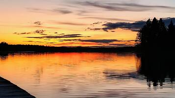 A calm lake at sunset with a wooden dock extending into the water.