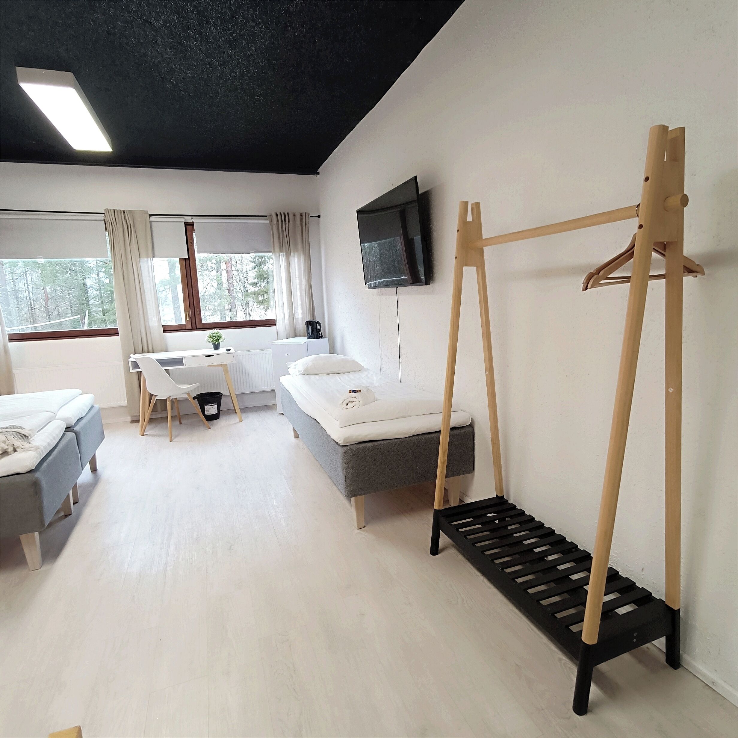 Une chambre d’hôtel équipée d’un lit, d’un bureau, d’une chaise, d’un téléviseur fixé au mur et d’une fenêtre avec des rideaux.