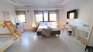 Una habitación de hotel moderna con una cama grande, un escritorio, un televisor y una ventana con cortinas.