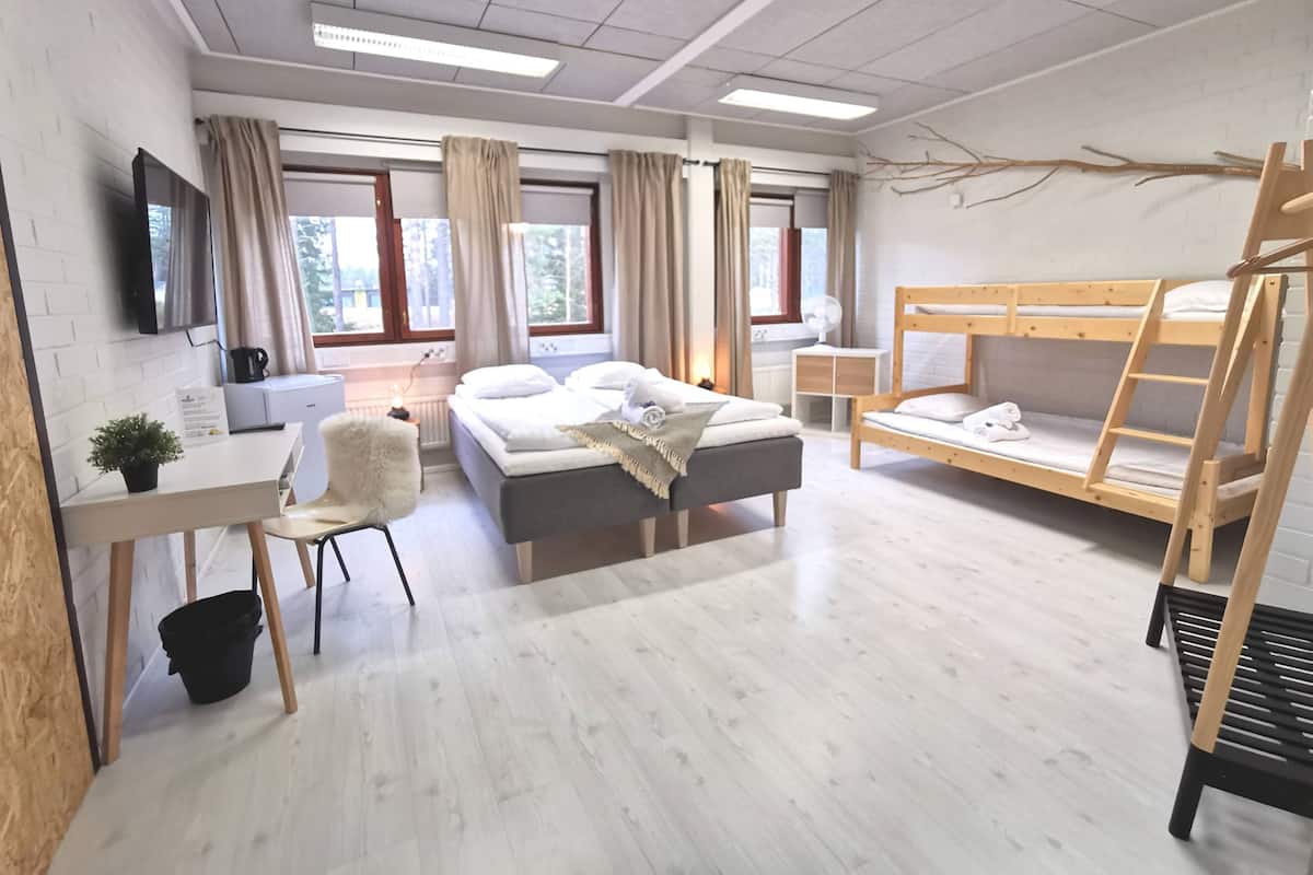 A modern hotel room with a bed, a desk, a chair, a TV, and a bunk bed.