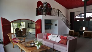 Un salon spacieux avec un canapé rose, une table basse en bois et un lustre.