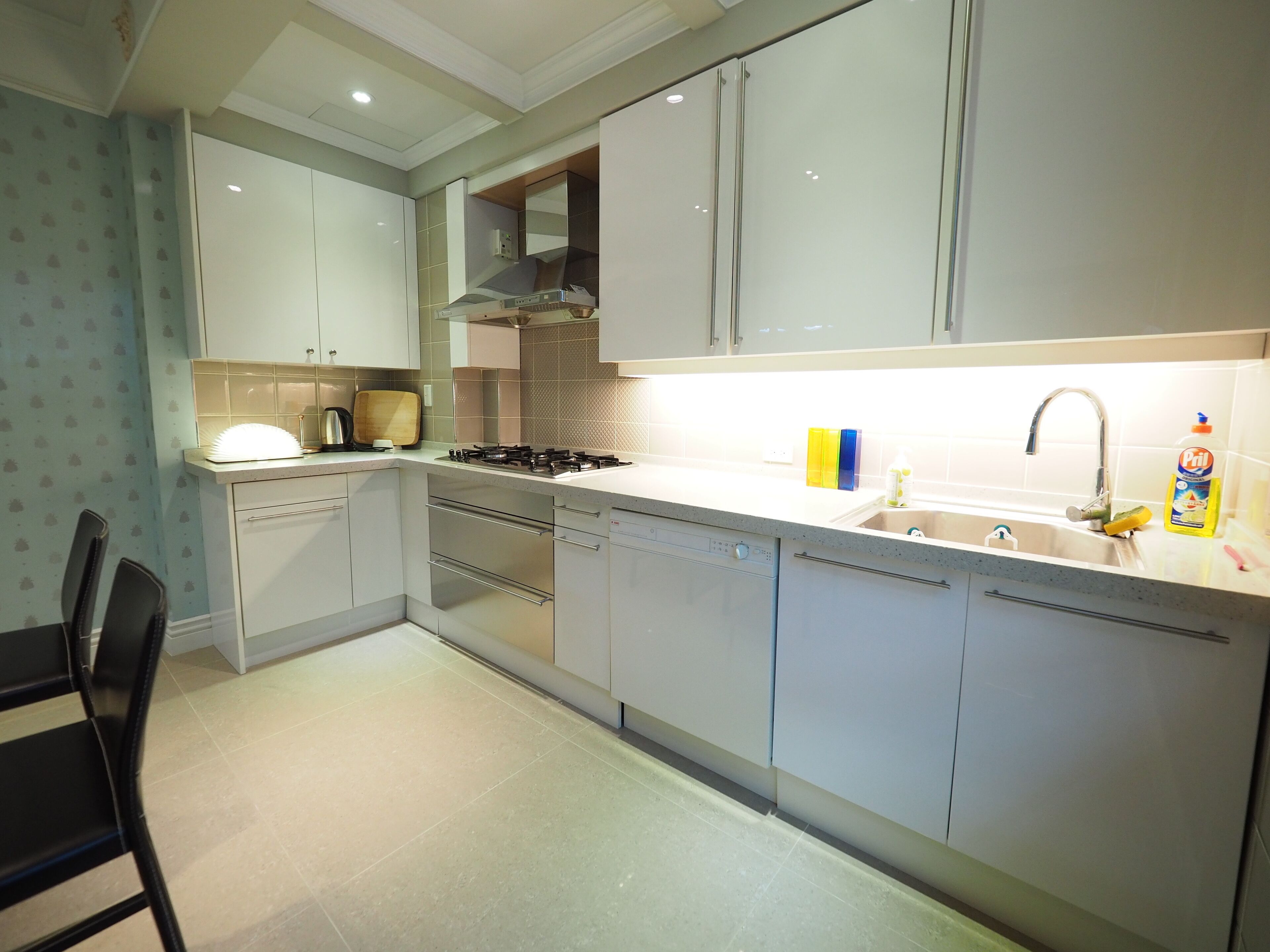 A modern kitchen with white cabinets, a stainless steel stove, and a sink with a faucet.