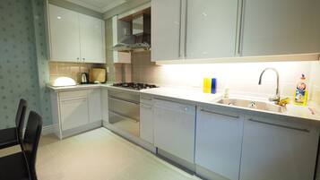 A modern kitchen with white cabinets, a stainless steel stove, and a sink with a faucet.