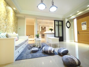 A modern living room with a sofa, a small table, and decorative stones. There is a kitchen area in the background with cabinets and a stove. - BR4&Zhongxiao Fuxing (Taipei)