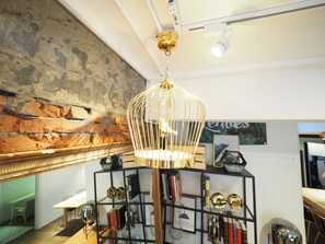 A room with a stone wall, a black shelving unit with decorative items, and a hanging gold-colored light fixture. - BR4&Zhongxiao Fuxing (Taipei)