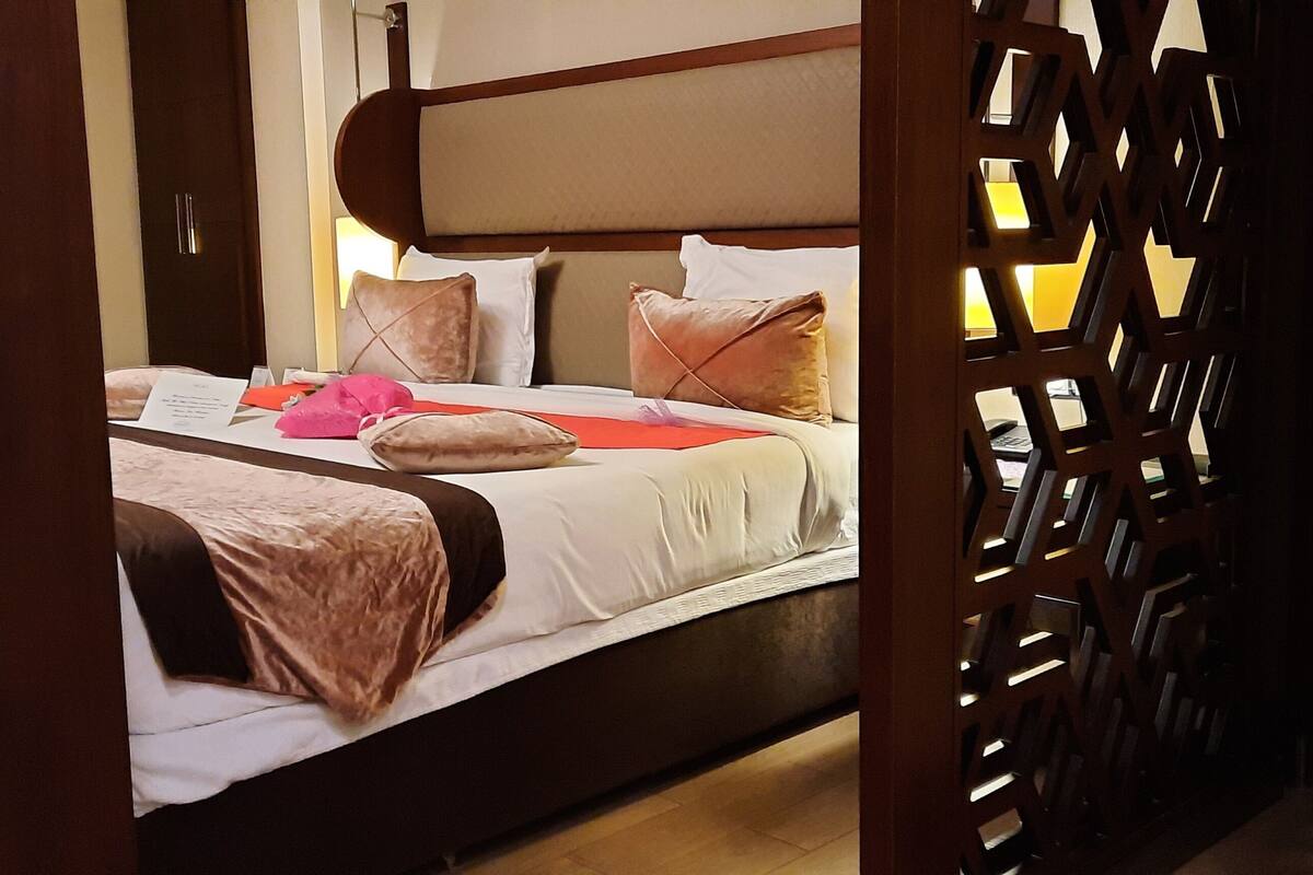 A neatly made bed with a headboard, pillows, and a blanket.