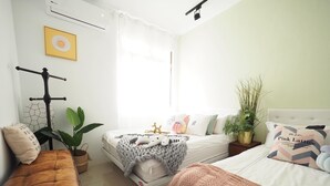 Ein helles Schlafzimmer mit Bett, Nachttischen, einem Sessel und einer Topfpflanze.