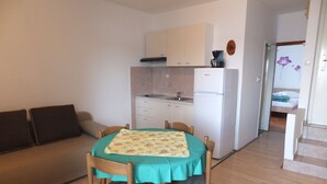 En kompakt bolig med et tekøkken, et spiseområde med bord og stole, samt en sofa.