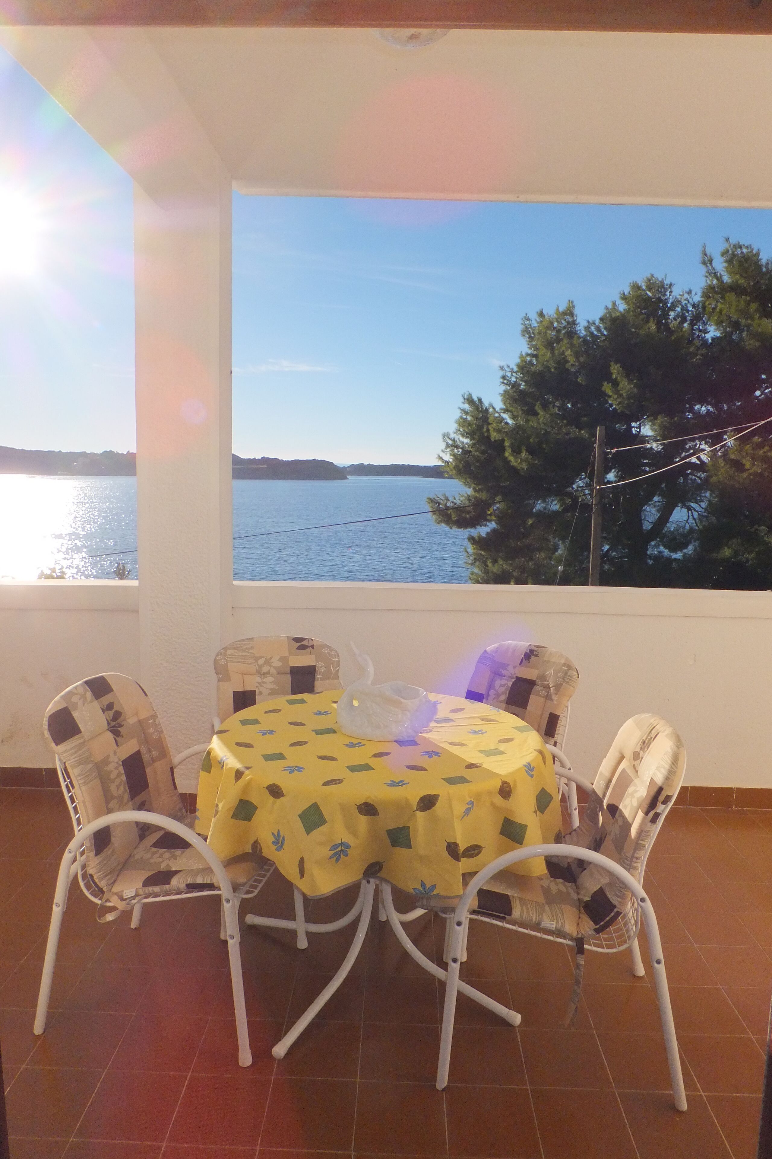 Una terraza con mesa y sillas, con vistas a un cuerpo de agua y árboles.