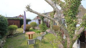 Un giardino con un tavolo e sedie, un recinto di legno e un albero con edera.