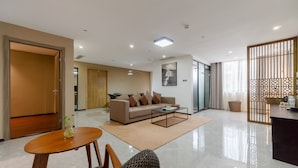 A modern living room with a sofa, coffee table, and a dining area with chairs. - Meeteem Boutique Hotel (Baise)