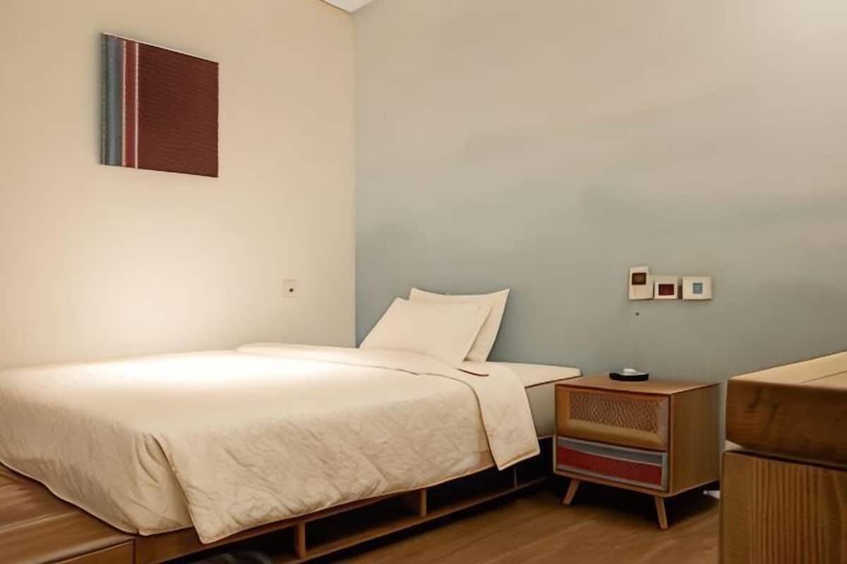 A bedroom with a bed, bedside table, and a small wooden cabinet.