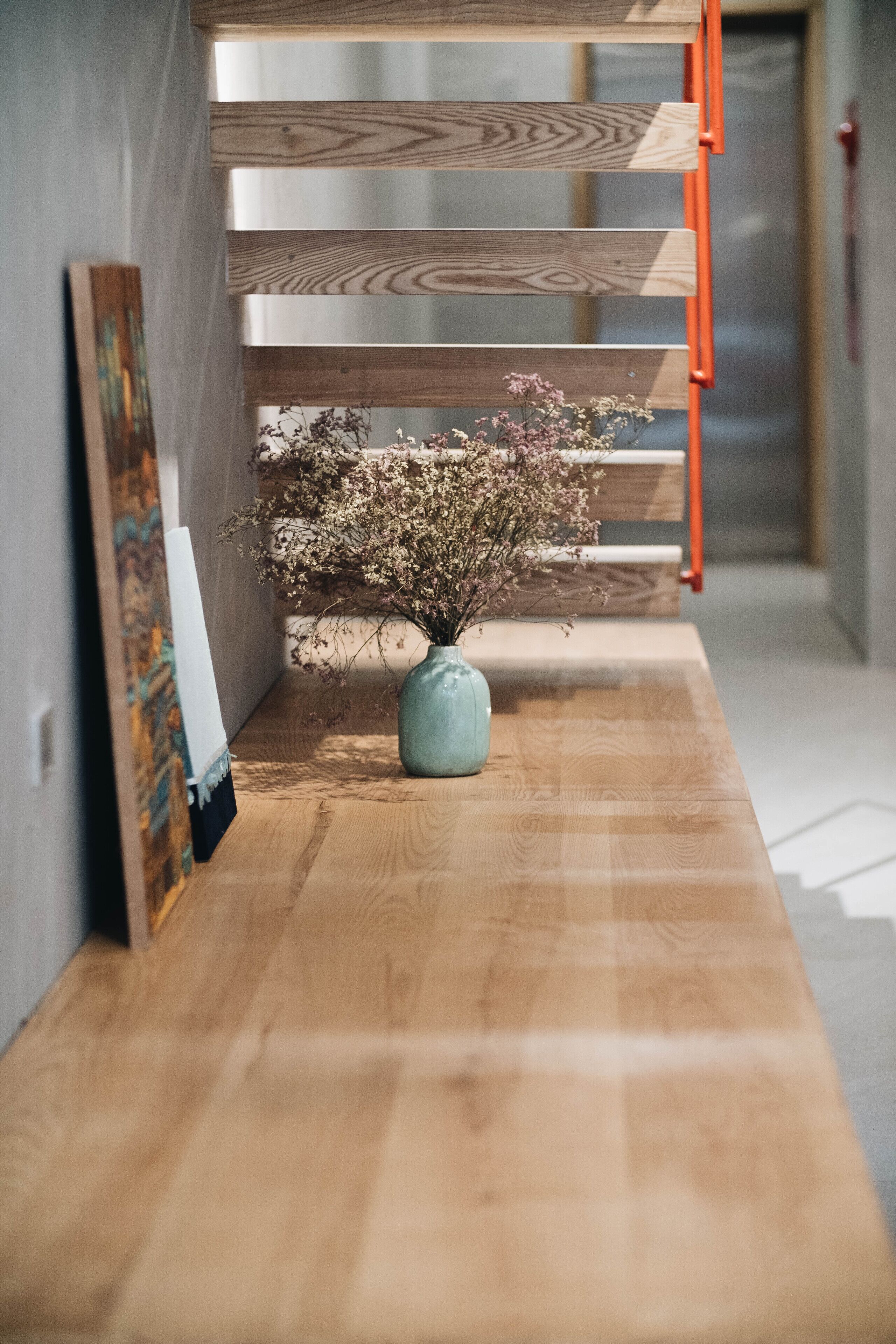 Un banco de madera con un jarrón de flores secas en un pasillo.