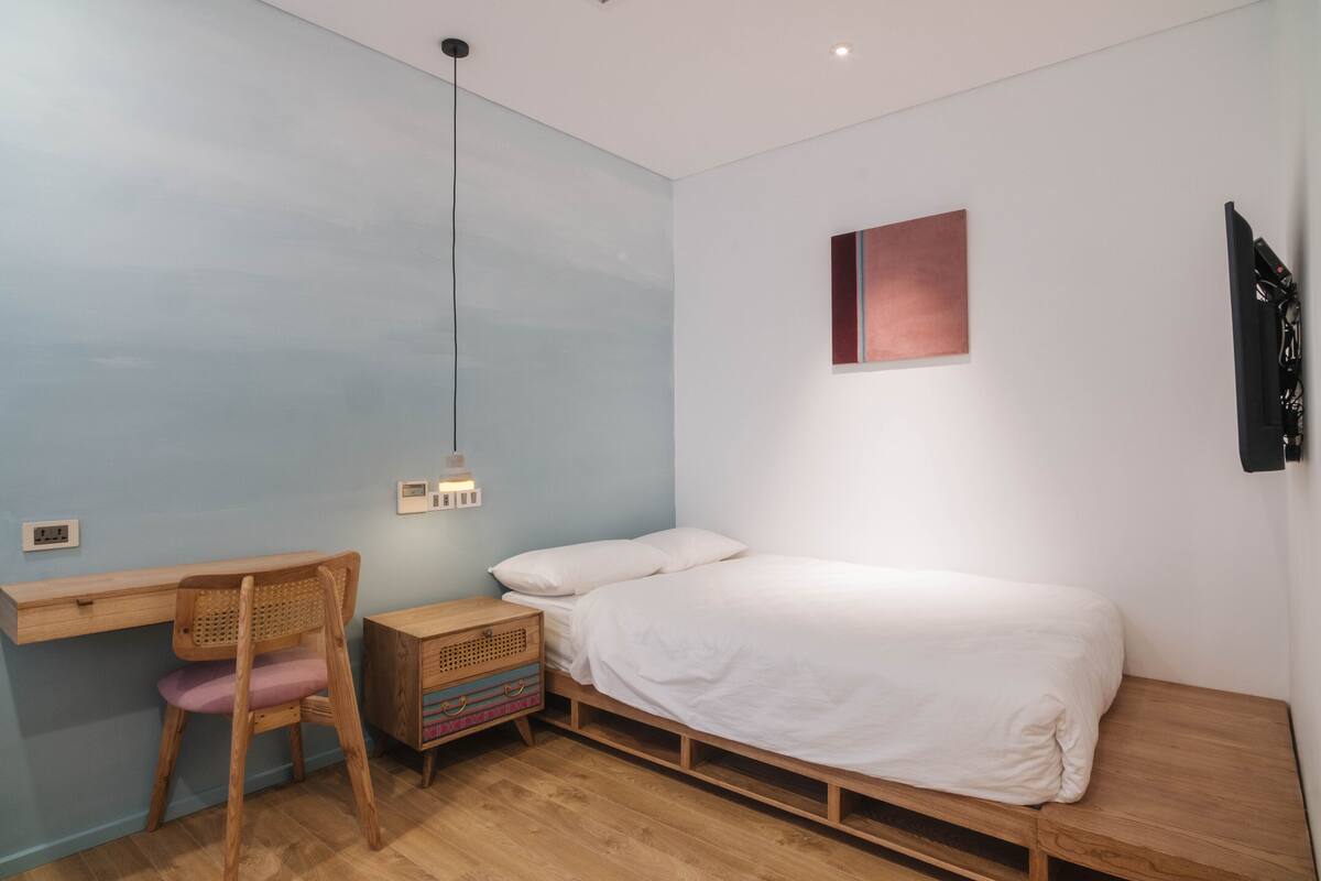 A bedroom with a wooden bed, a desk, and a chair.