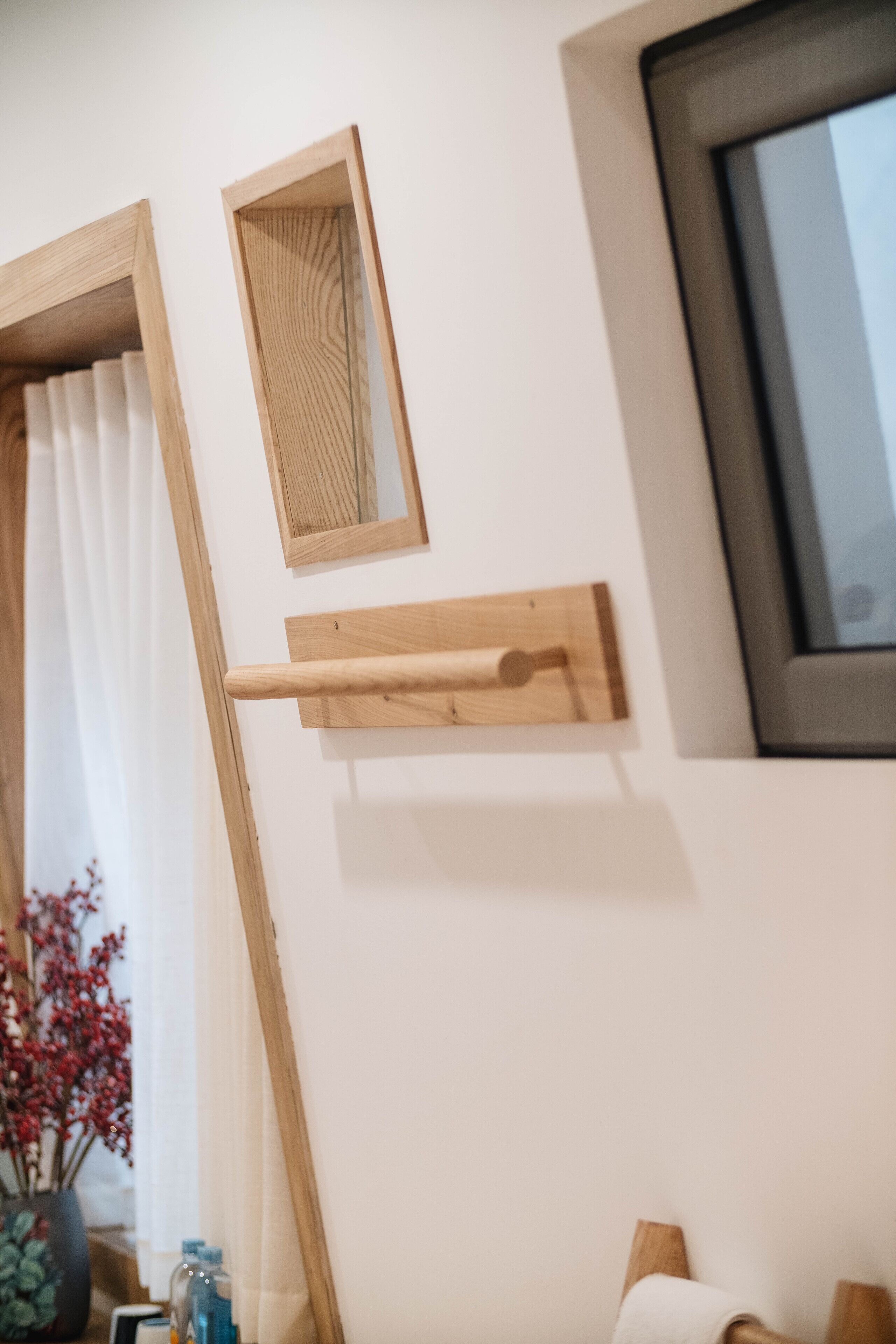 A room with a wooden shelf, a mirror, and a window.