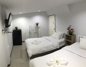 Une chambre d’hôtel avec deux lits, une armoire, un miroir, une plante et une décoration artistique réalisée avec des serviettes.