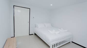 A white bedroom with a bed, a door, and a wooden bench.