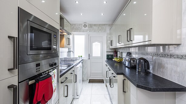 Een moderne keuken met roestvrijstalen apparatuur, witte kasten en een zwart aanrecht.