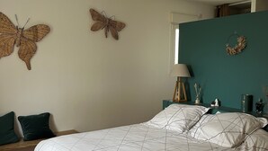 A bedroom with a bed, two wall-mounted butterflies, a window, and a teal accent wall.