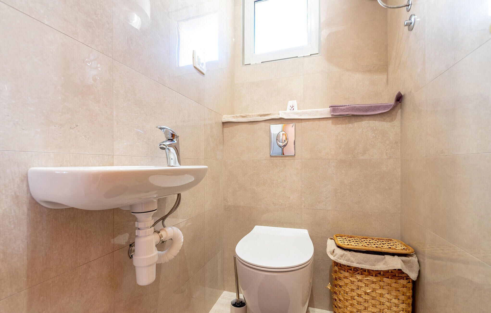 A bathroom with a sink, toilet, and a small wicker basket.