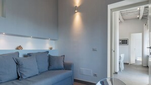 Een moderne woonkamer met een bank, een glazen tafel en een gang naar een keuken.