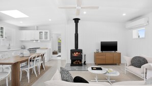 Ein modernes Wohnzimmer mit Kamin, weißen Möbeln und einem Fernseher.