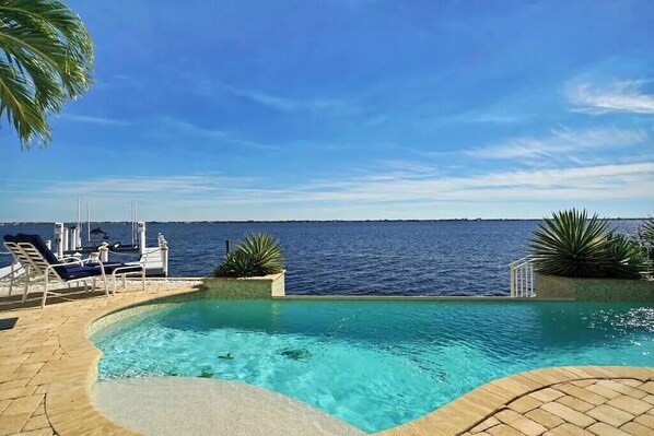 Relax by the oceanfront pool surrounded by lush greenery and comfortable lounge chairs.