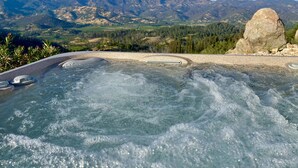 A hot tub with a mountain view, surrounded by natural landscape and a large rock formation.