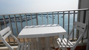 A balcony with a white table and chairs, overlooking a marina with boats. - WATERFRONT APARTMENT (Jard-sur-Mer)