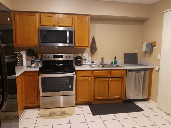 A kitchen with wooden cabinets, stainless steel appliances, a microwave, stove, and a dishwasher. - Charming Townhouse with pool (Phoenix)