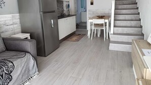 Een moderne keuken met een roestvrijstalen koelkast, witte kastjes en een houten eettafel met stoelen.