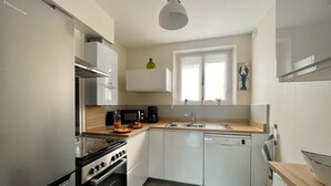 Une cuisine moderne avec des meubles blancs, un four encastré, un four à micro-ondes et un lave-vaisselle.