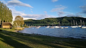 A lakeside view with boats, grassy areas, and a small building.