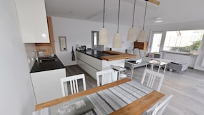 A modern kitchen with white cabinetry, a wooden island, and pendant lighting.